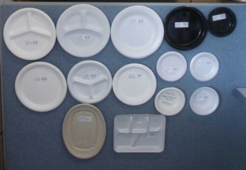 photo of a variety of disposable plates that are sold by C&C Suppliers on display hanging on a blue wall