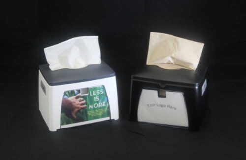 photo of 2 napkin dispensers sold by C&C Suppliers, one white with gray and one black, both with a display panel for customization, arranged on a black background